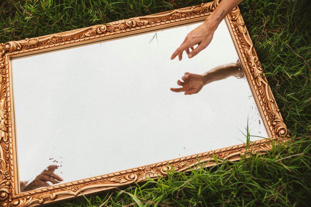 a person reaching out their hand to touch a mirror
