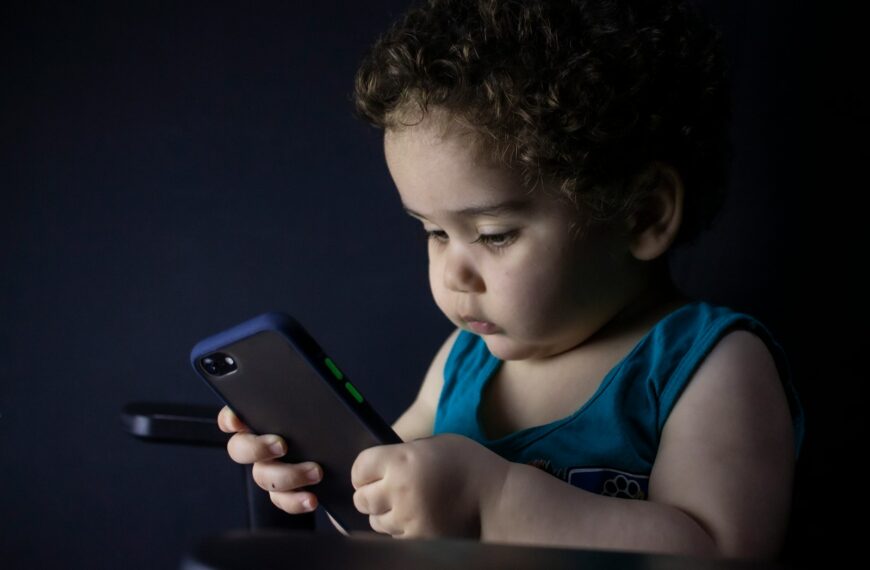 boy in blue tank top holding black iphone 5