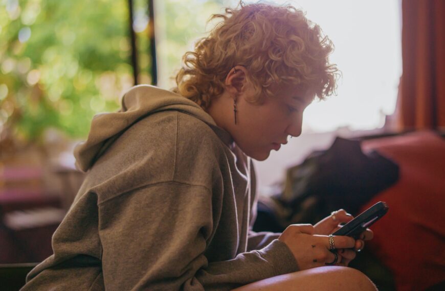 Portrait of a nonbinary autistic person using their mobile phone indoors
