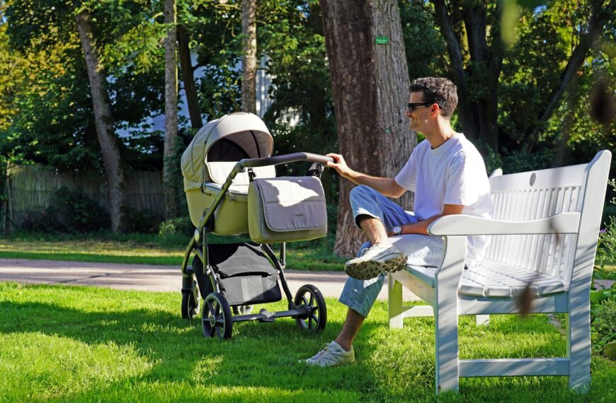 a man sitting on a bench next to a baby stroller