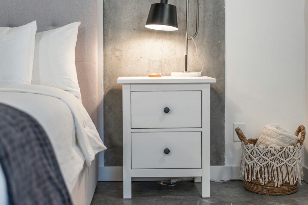a bedroom with a bed and a nightstand with a lamp on top of it