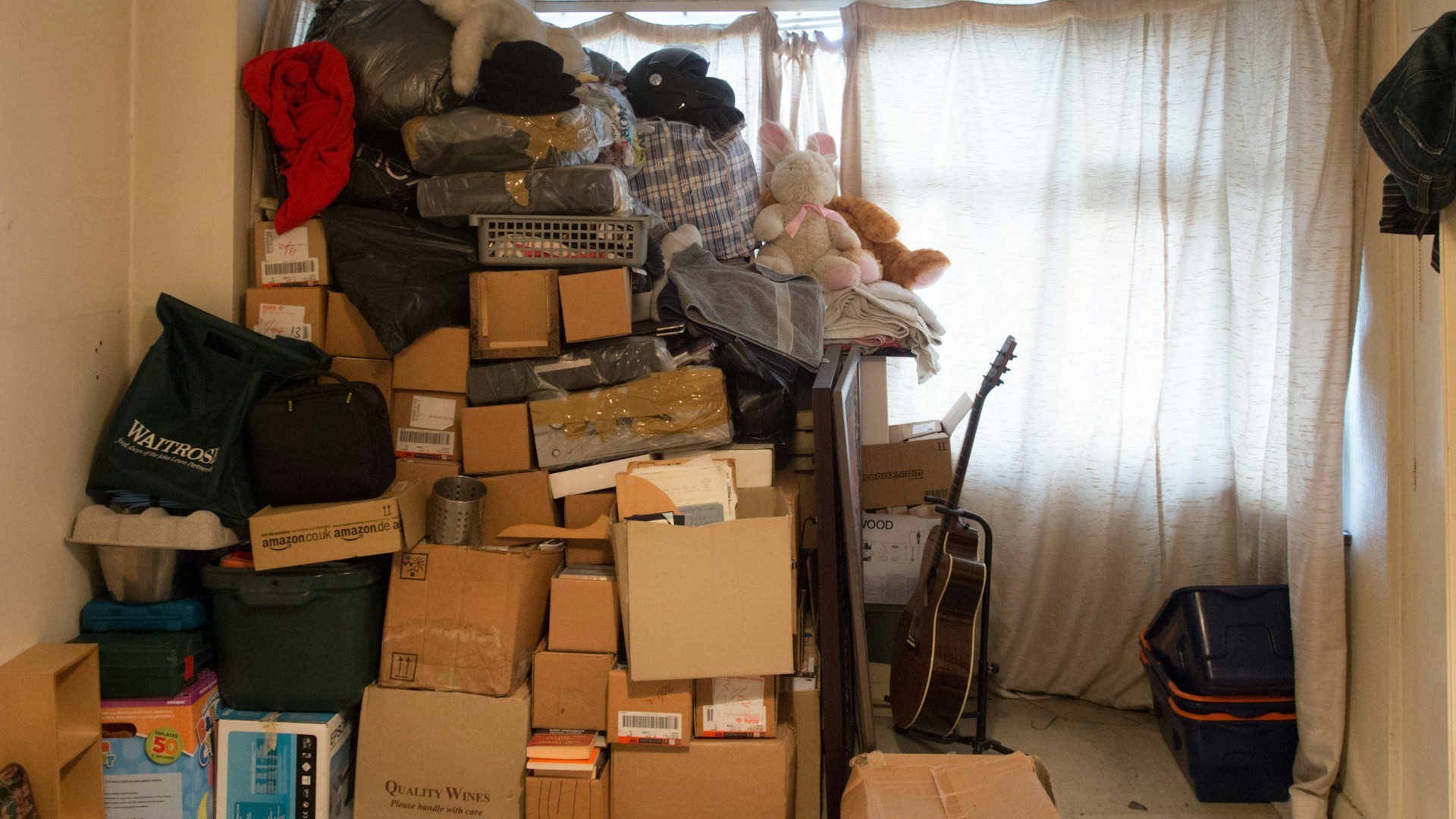 Cardboard boxes and household items stacked high in a crowded storage room.