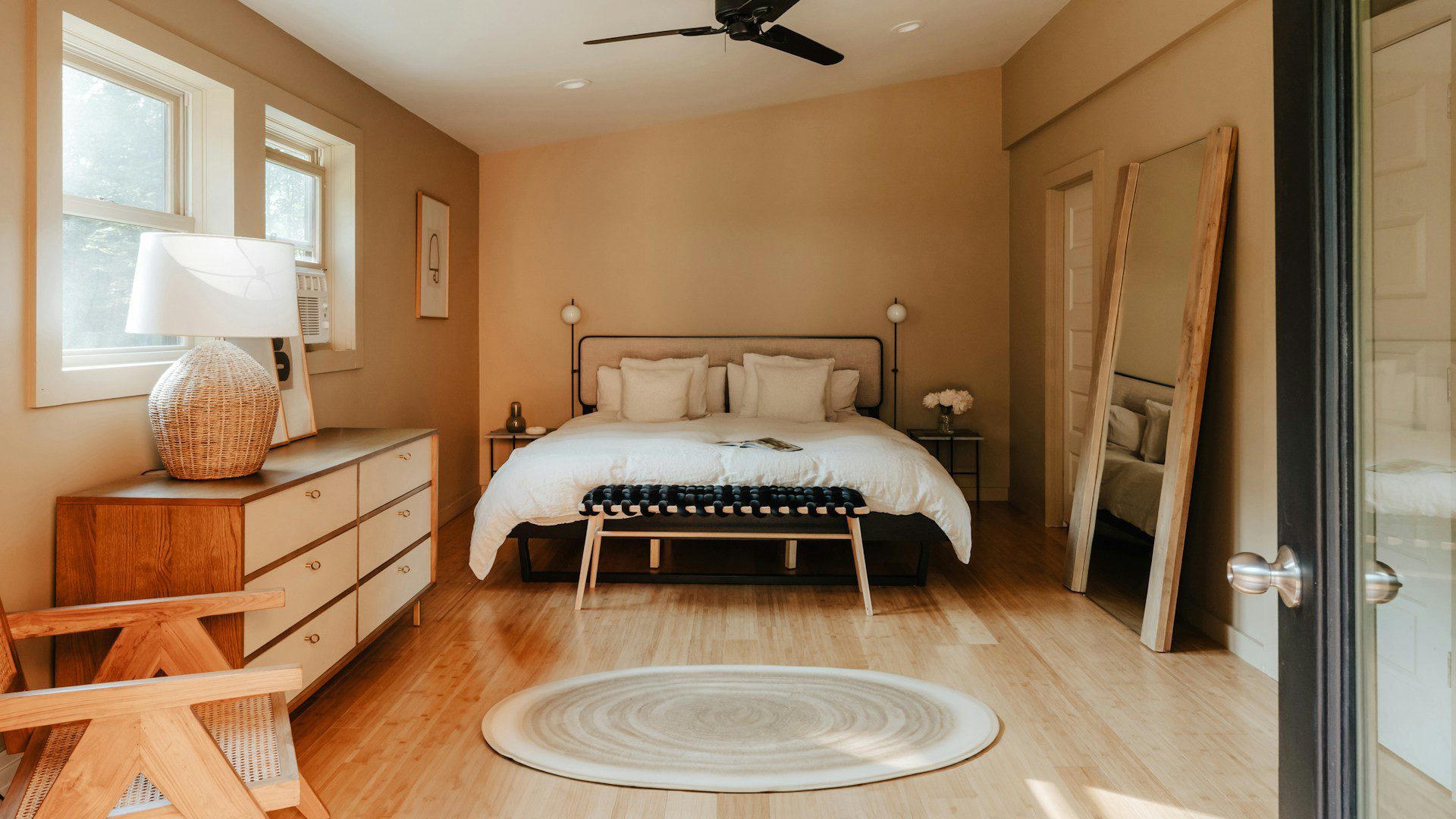 A sunlit bedroom with a wooden dresser beside the bed.