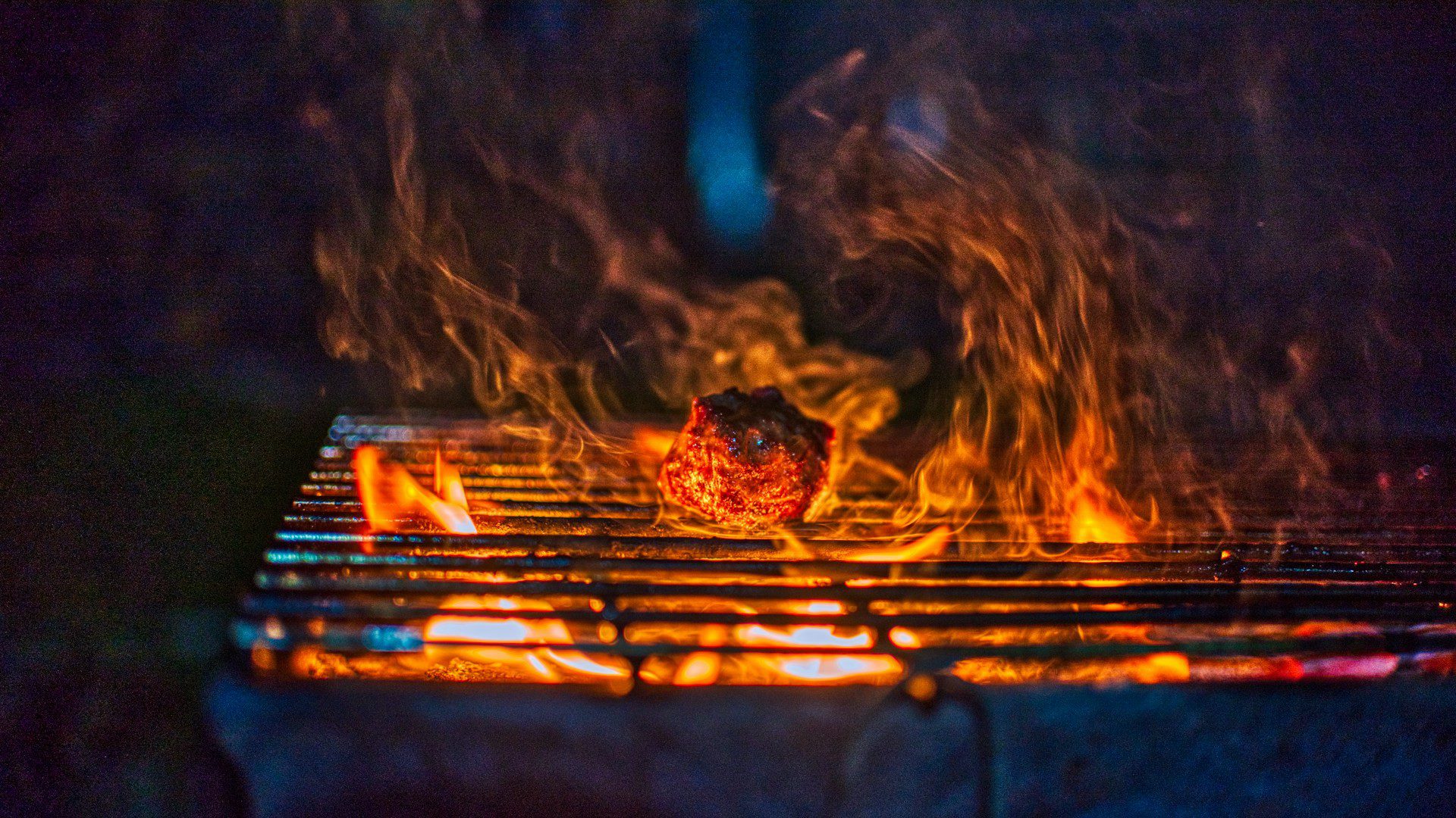 Flames and glowing coals in a charcoal grill.