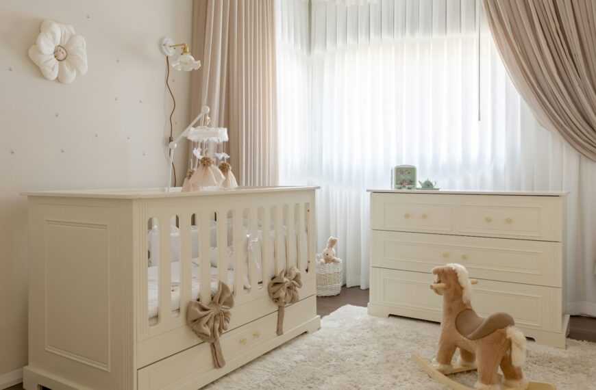 A cream-colored nursery with a white crib, dresser and plush rocking horse.