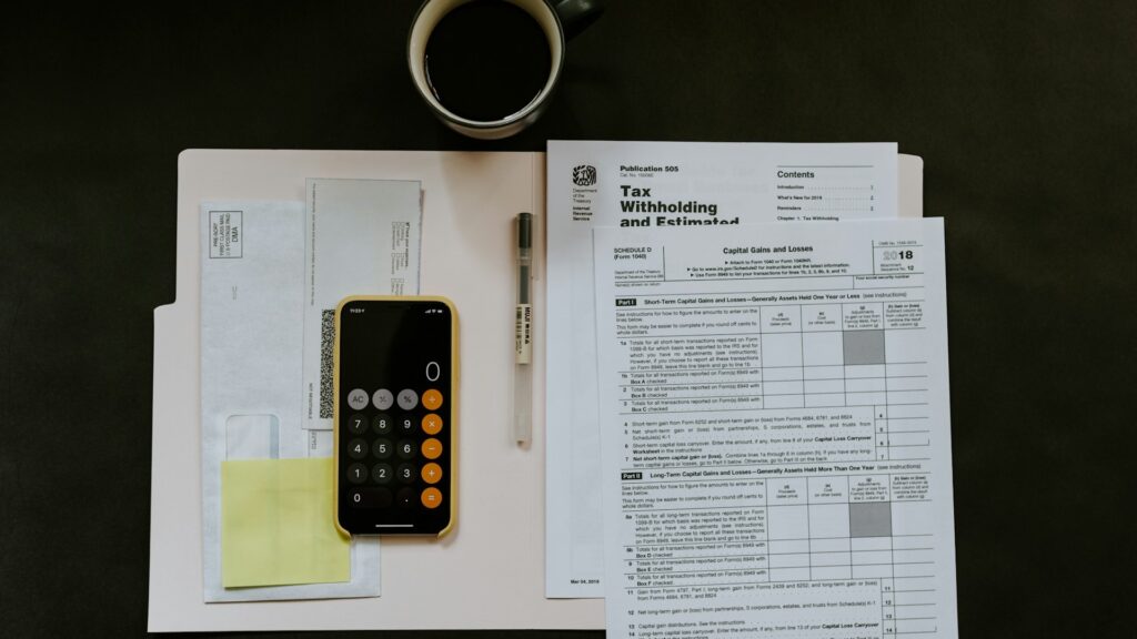A tax withholding form on a desk beside a smartphone calculator.