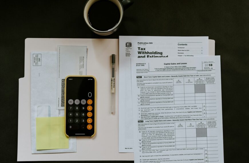 A tax withholding form on a desk beside a smartphone calculator.