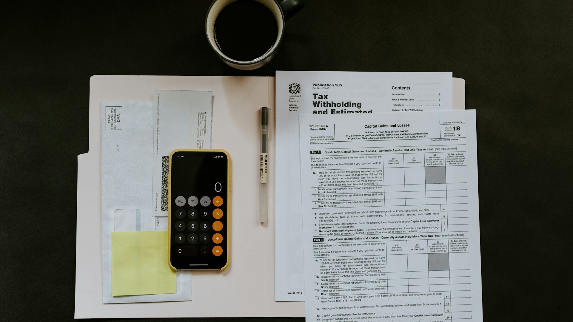 A tax withholding form on a desk beside a smartphone calculator.