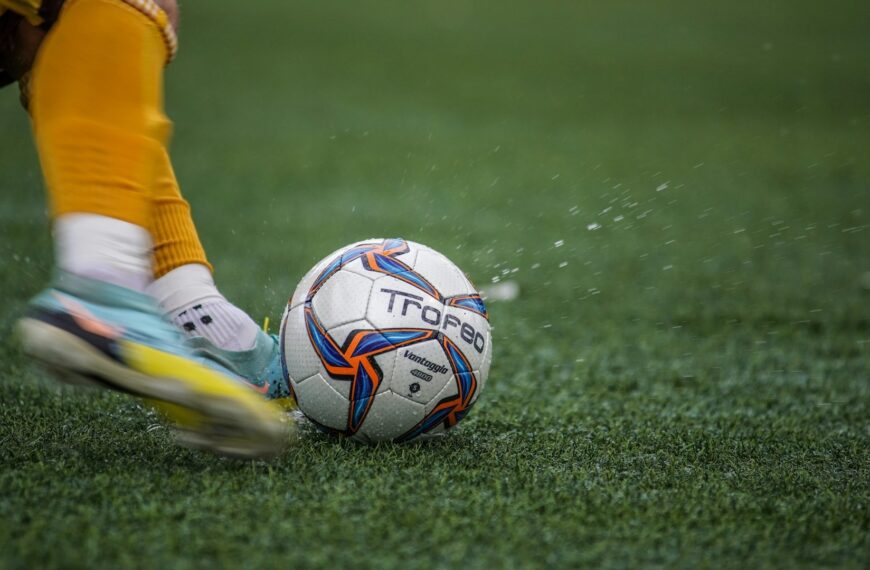 A soccer ball and cleats in motion on a green field.