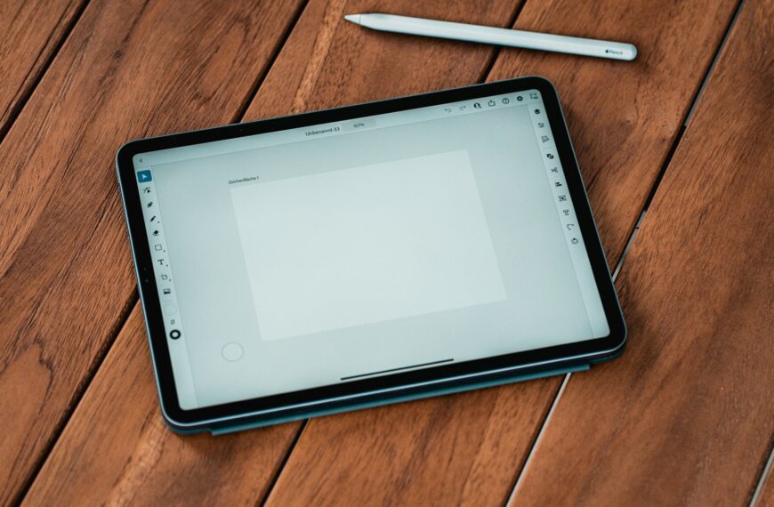 A tablet and stylus resting on a wooden table.