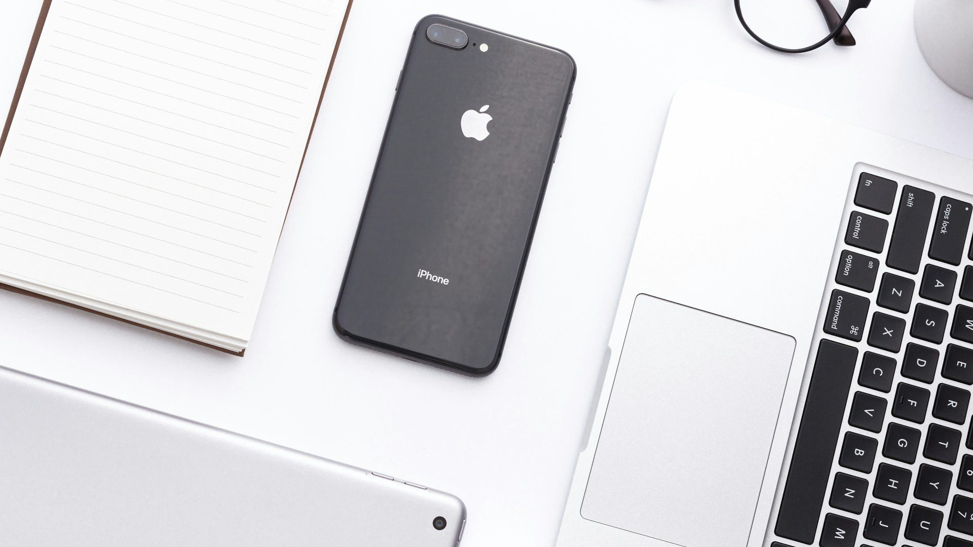 A smartphone resting beside a laptop on a desk.