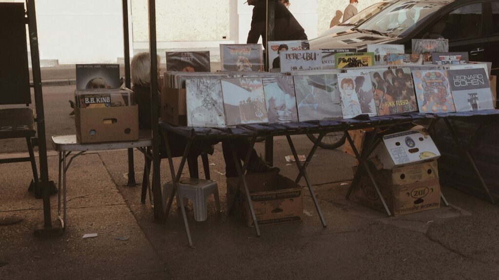 Records and goods laid out on tables at an outdoor sale.