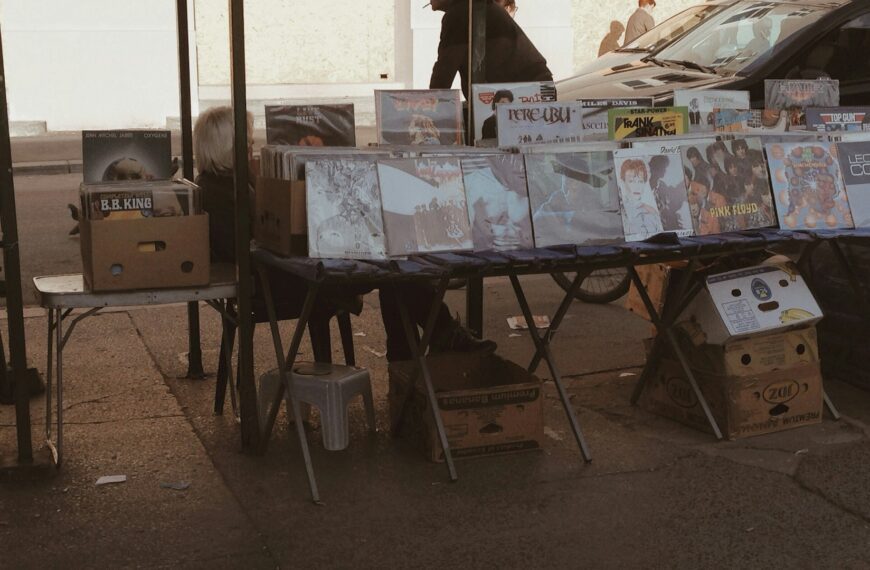 Records and goods laid out on tables at an outdoor sale.