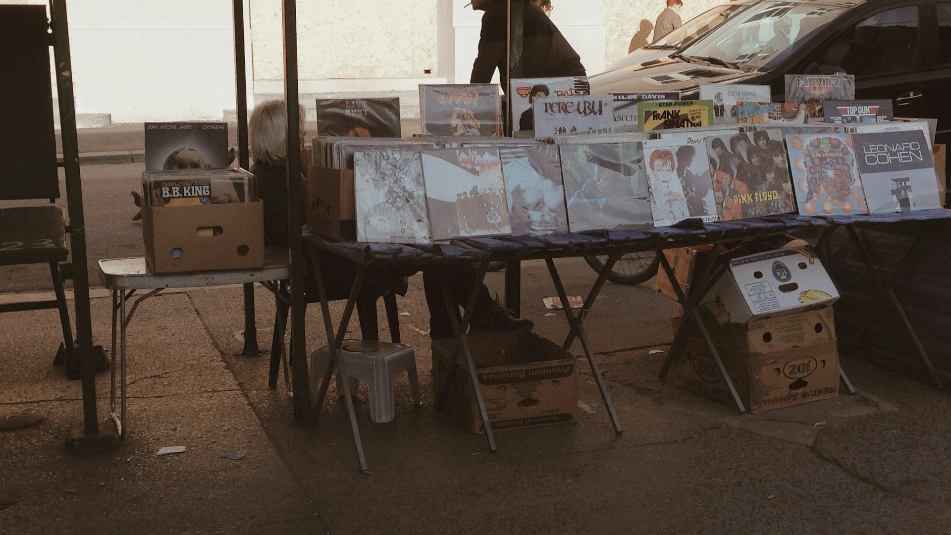 Records and goods laid out on tables at an outdoor sale.