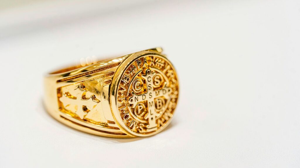 A gold signet ring on a white surface.