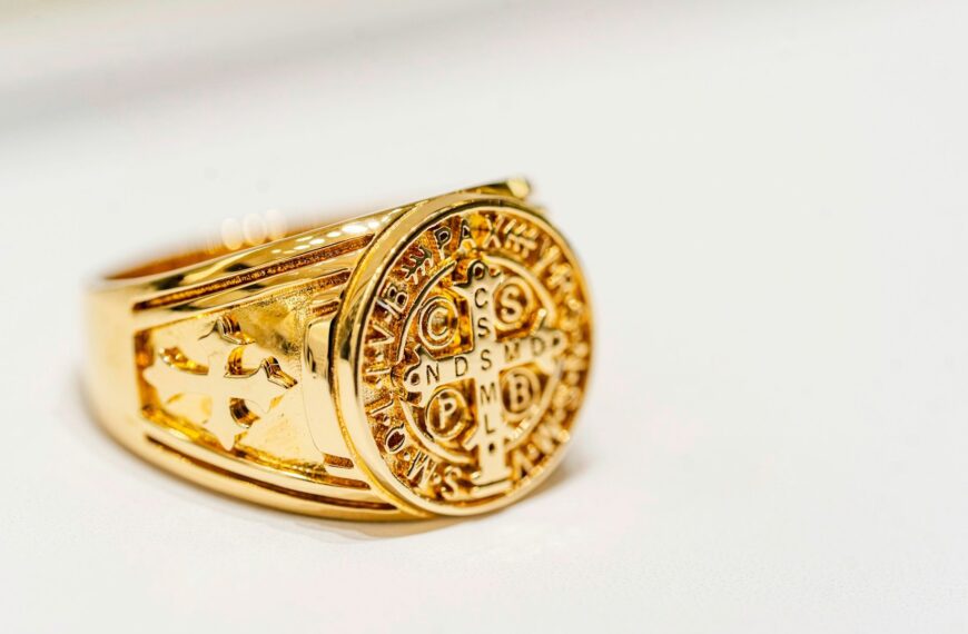 A gold signet ring on a white surface.