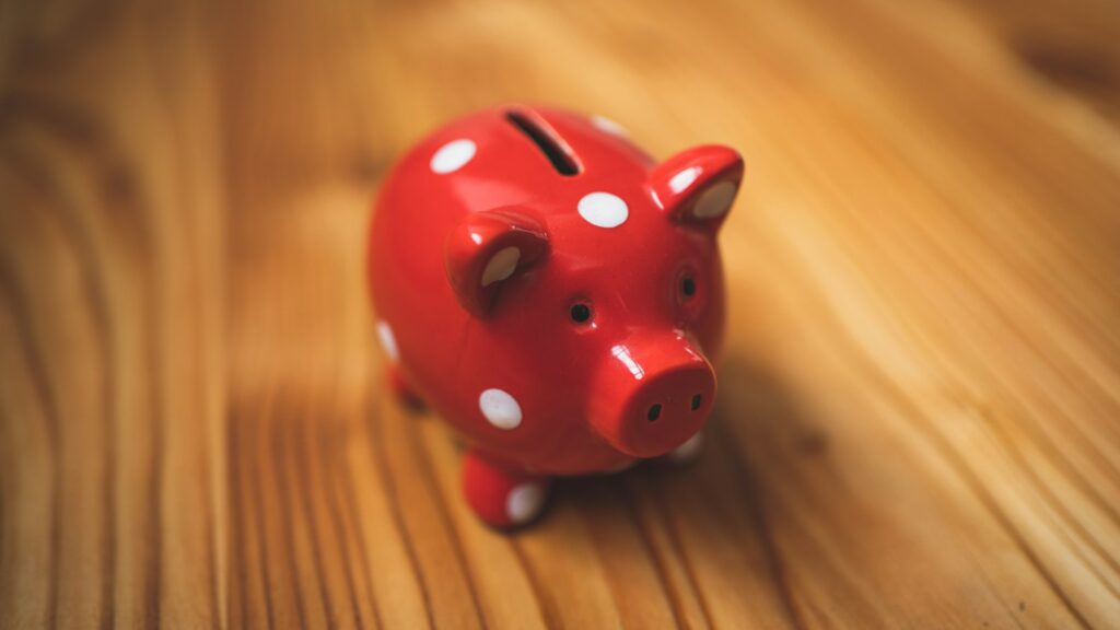 A red polka dot piggy bank on a wooden table.