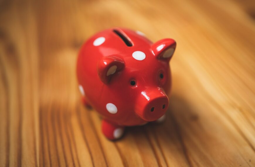 A red polka dot piggy bank on a wooden table.