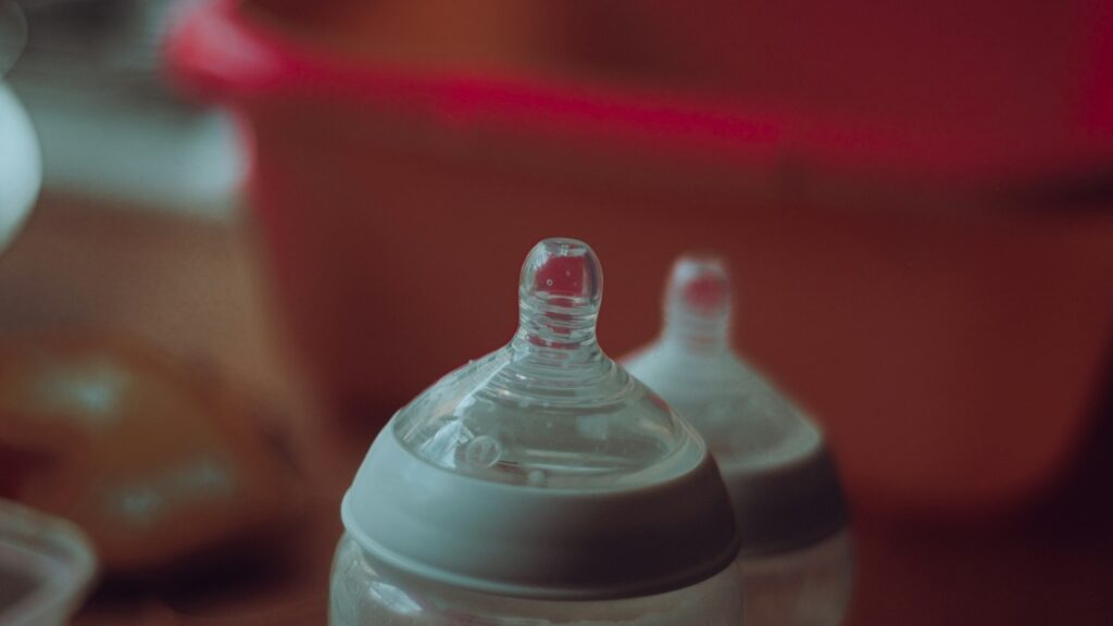 Two clear baby bottles on a red table.