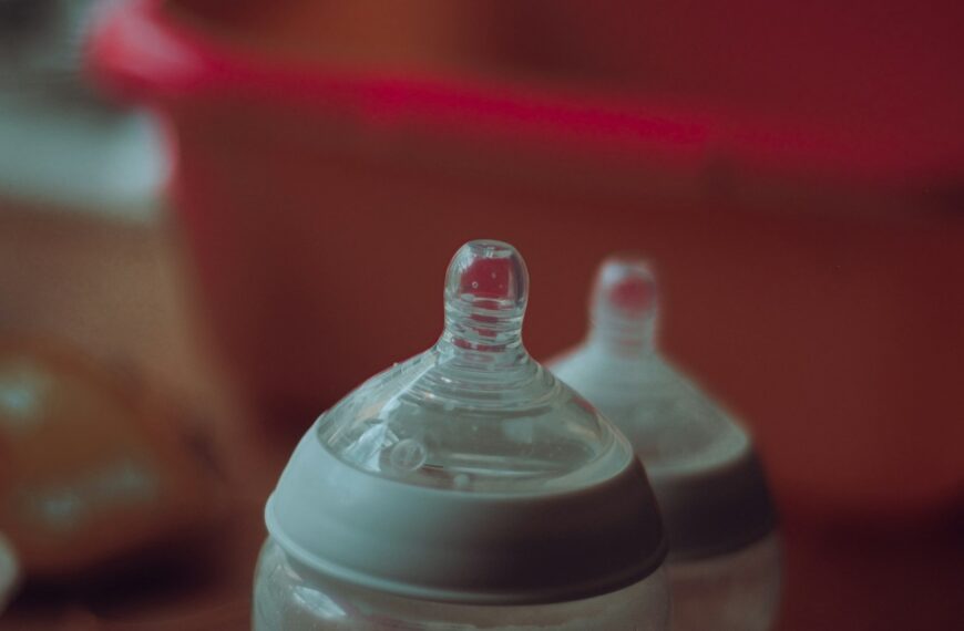 Two clear baby bottles on a red table.
