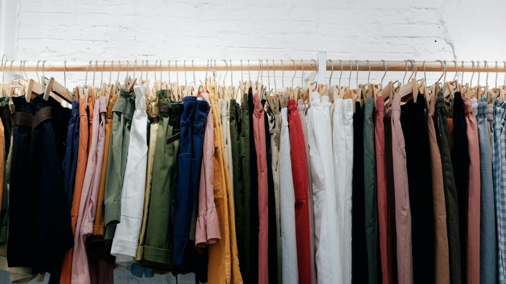 Colorful clothes hanging on a wooden wall rack.