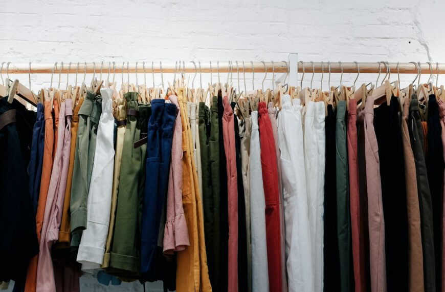 Colorful clothes hanging on a wooden wall rack.