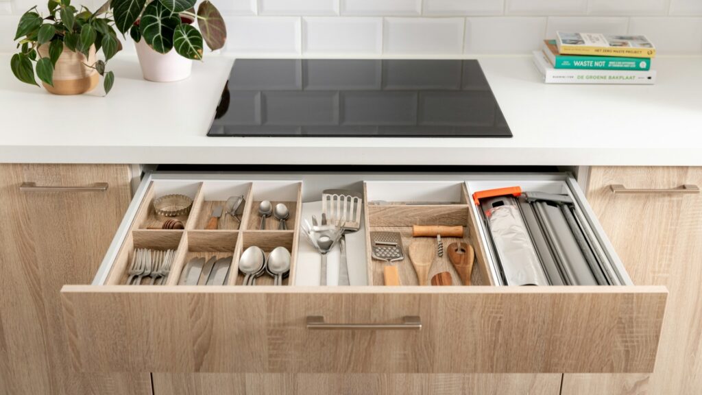 An open kitchen drawer filled with utensils and small tools (Unsplash photo by Orgalux).