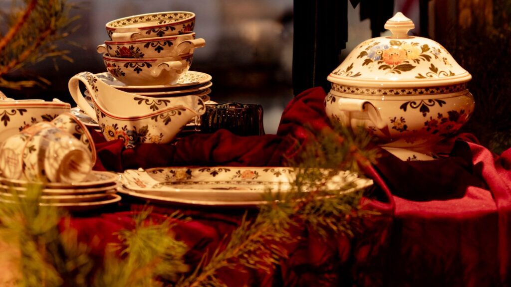 A holiday table set with patterned teacups, plates and a covered tureen (Unsplash photo by laura adai).