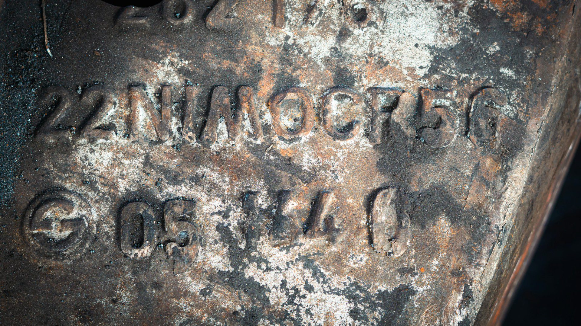 A worn cast iron surface with stamped lettering and numbers (Unsplash photo by Davide Buttani).