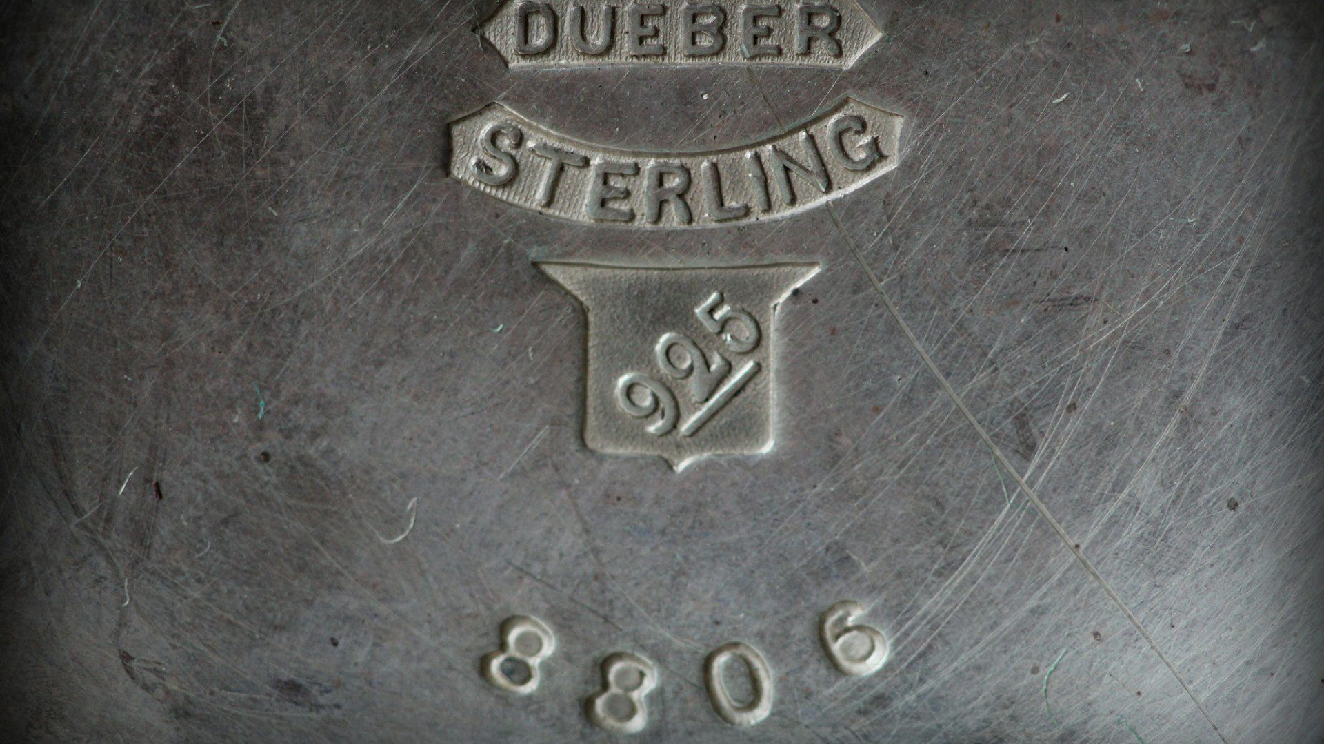 A close-up of a maker's mark stamped into sterling silver, reading Dueber Sterling 925 (Unsplash photo by Anne Nygård).