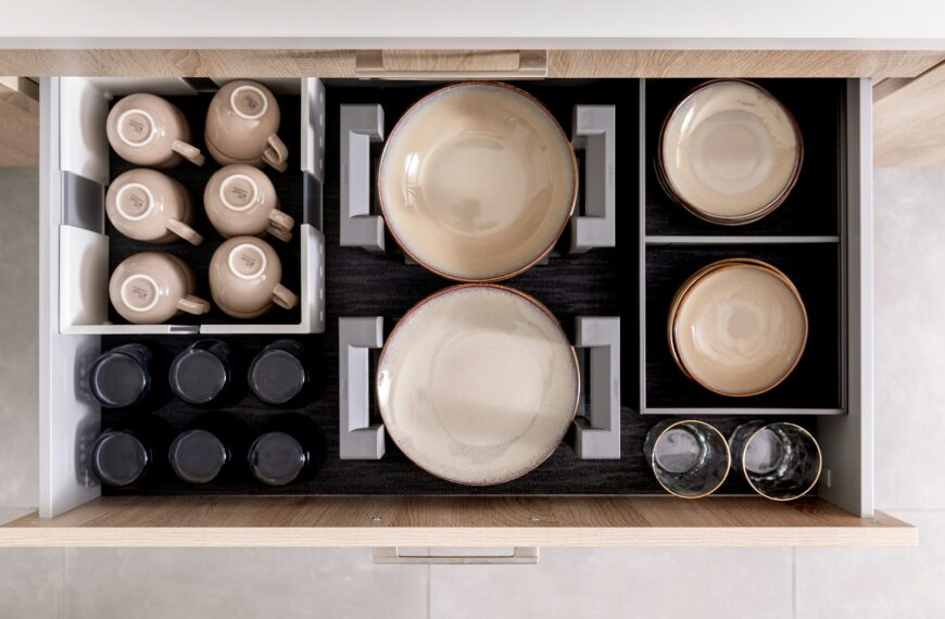 Unsplash photo by Orgalux showing an organized kitchen drawer with dishes and cups in organizers