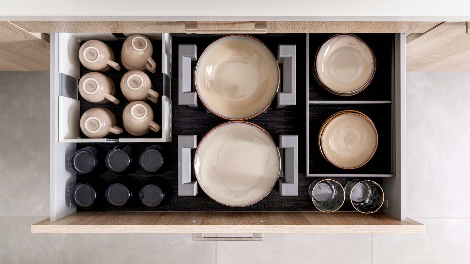 Unsplash photo by Orgalux showing an organized kitchen drawer with dishes and cups in organizers