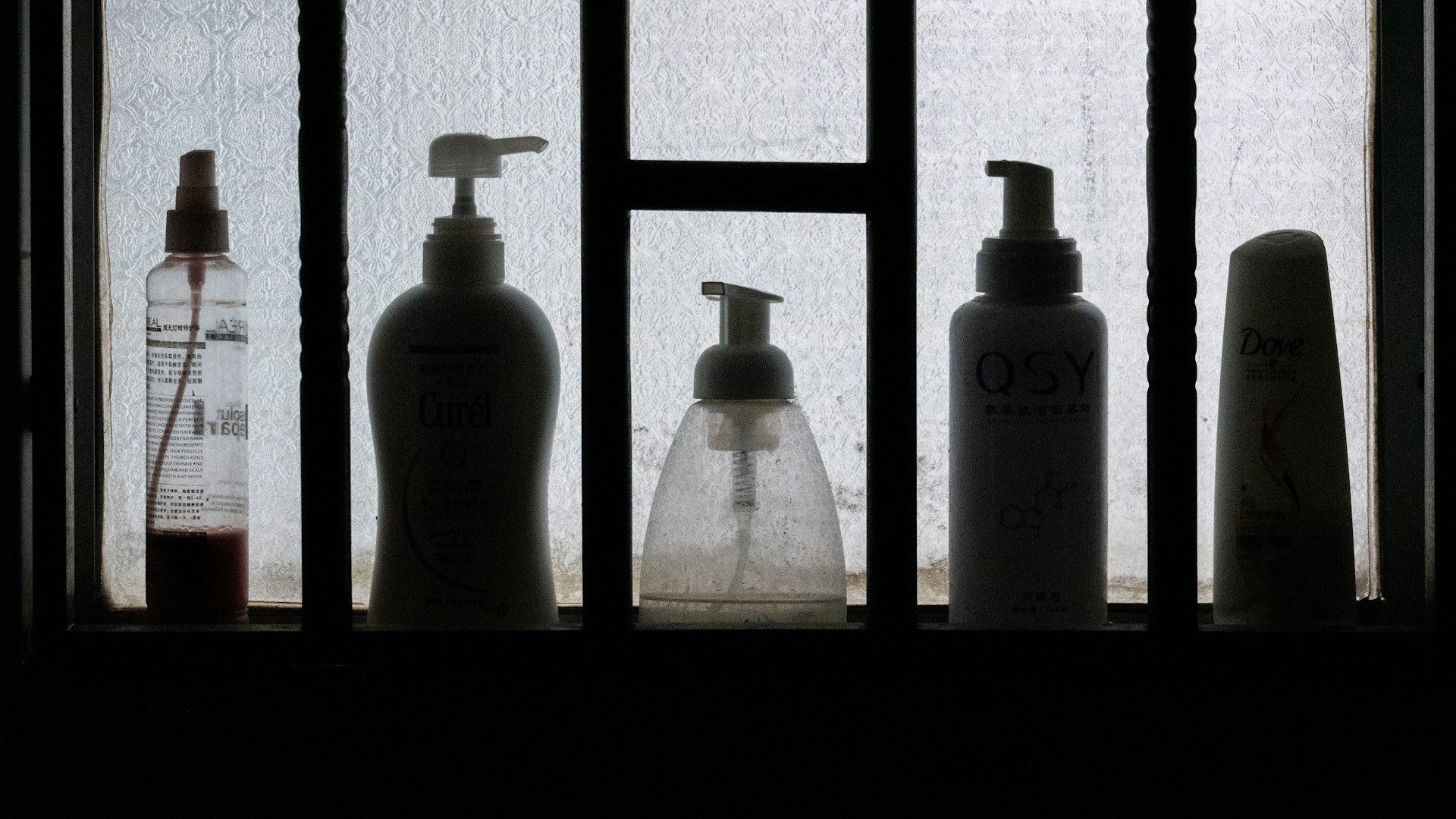 Unsplash photo by Lingchor showing three toiletry bottles on a black wooden shelf
