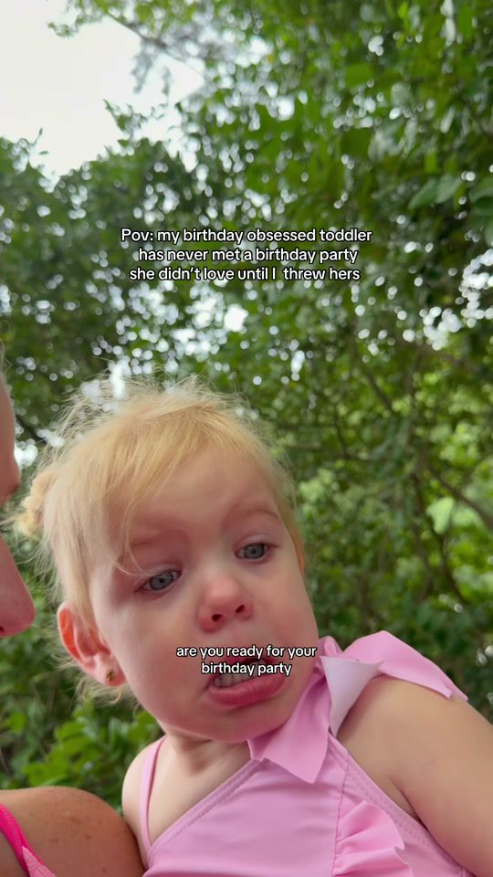 A mom holding her toddler daughter, dressed in a pink birthday girl swimsuit, on the way to the birthday party thrown for her (still from the creator's TikTok video)