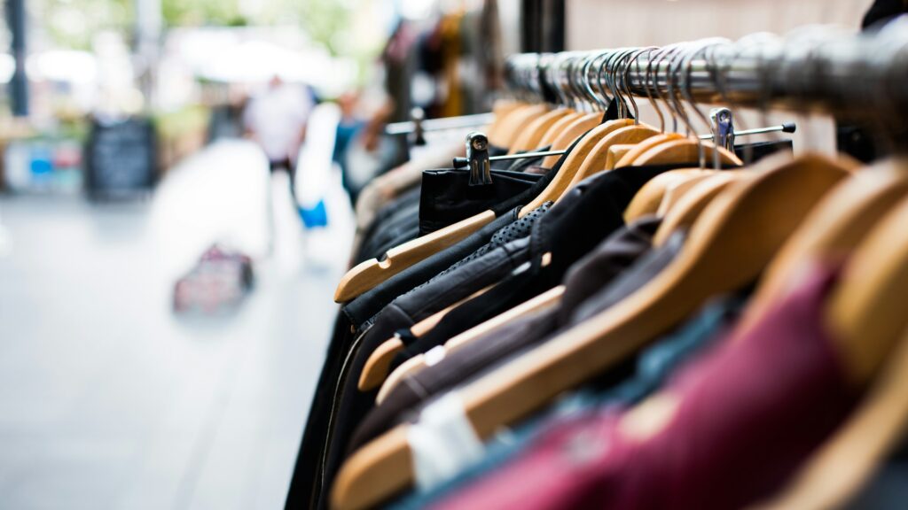 Clothes hang on hangers on a rack in a clothing store.