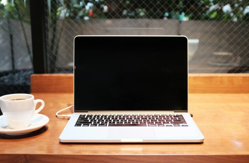 A laptop sits on a desk beside a white coffee mug.