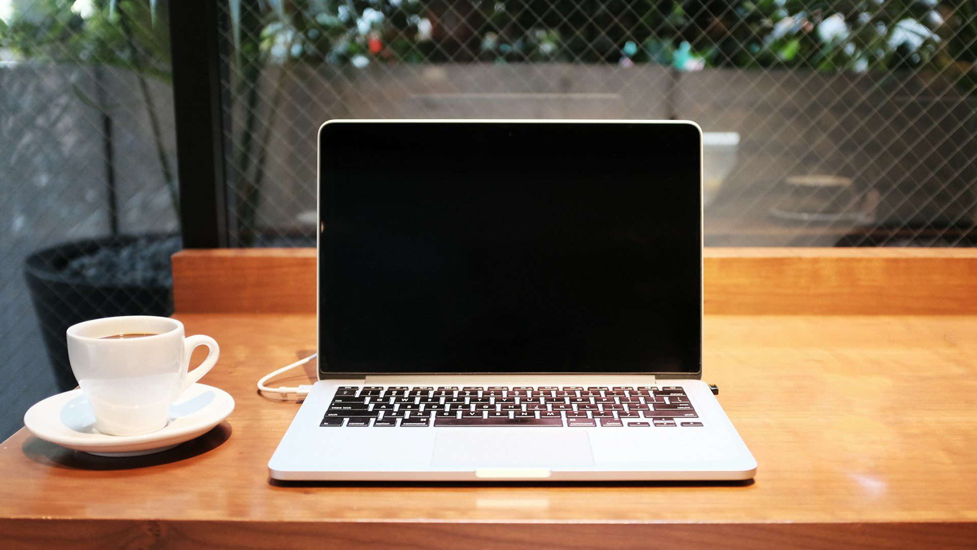 A laptop sits on a desk beside a white coffee mug.