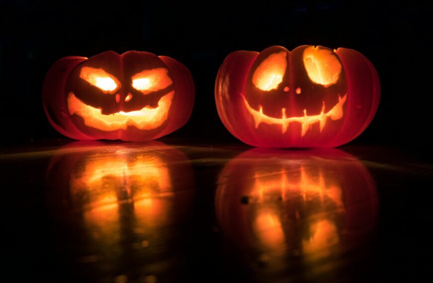 Two carved jack-o-lanterns glow in the dark.
