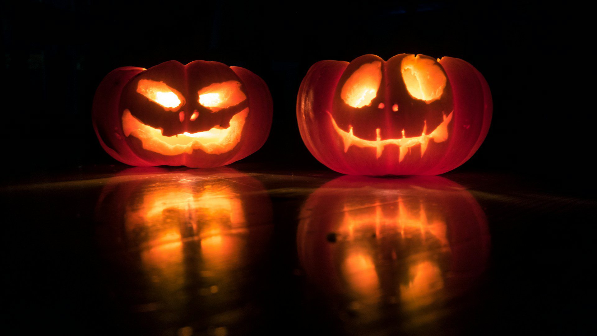 Two carved jack-o-lanterns glow in the dark.