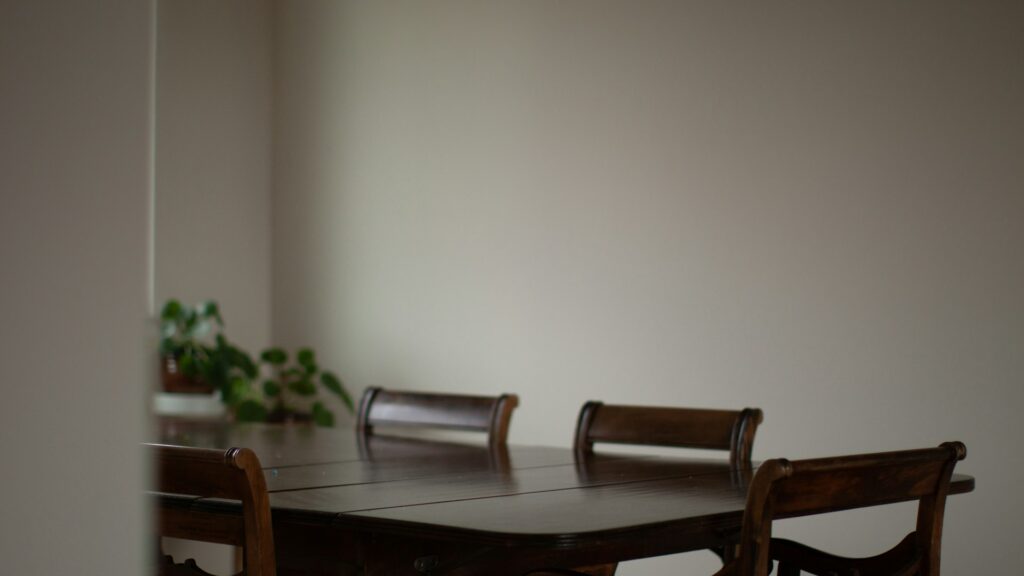 An empty wooden dining table with chairs sits ready for a family meal.