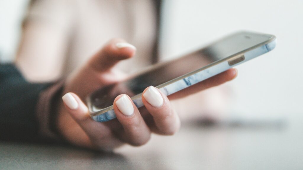 A hand holds a smartphone with a marble case.