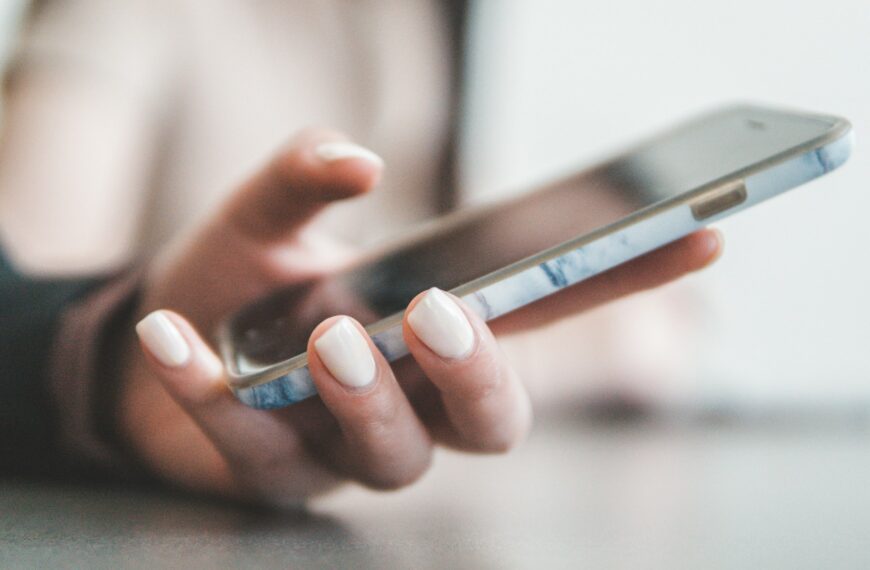 A hand holds a smartphone with a marble case.