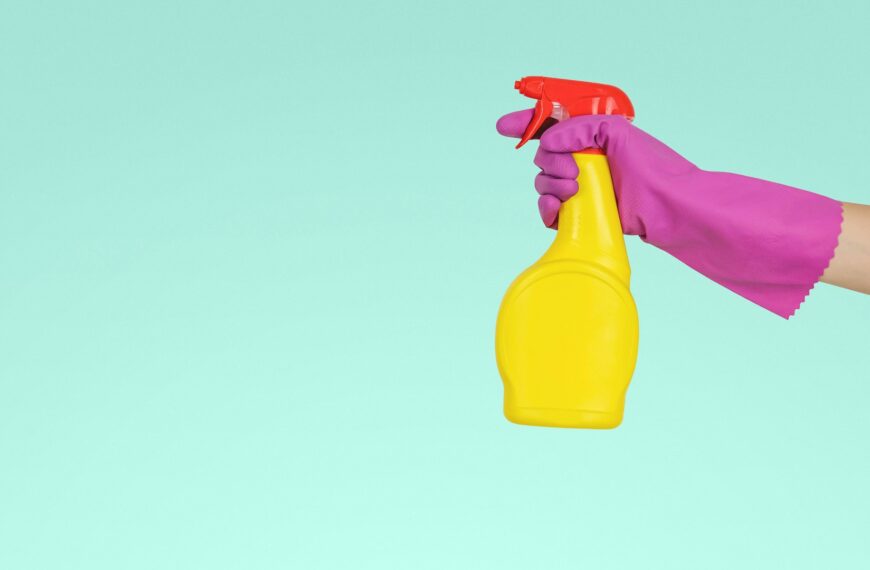 A hand holds a yellow plastic spray bottle.