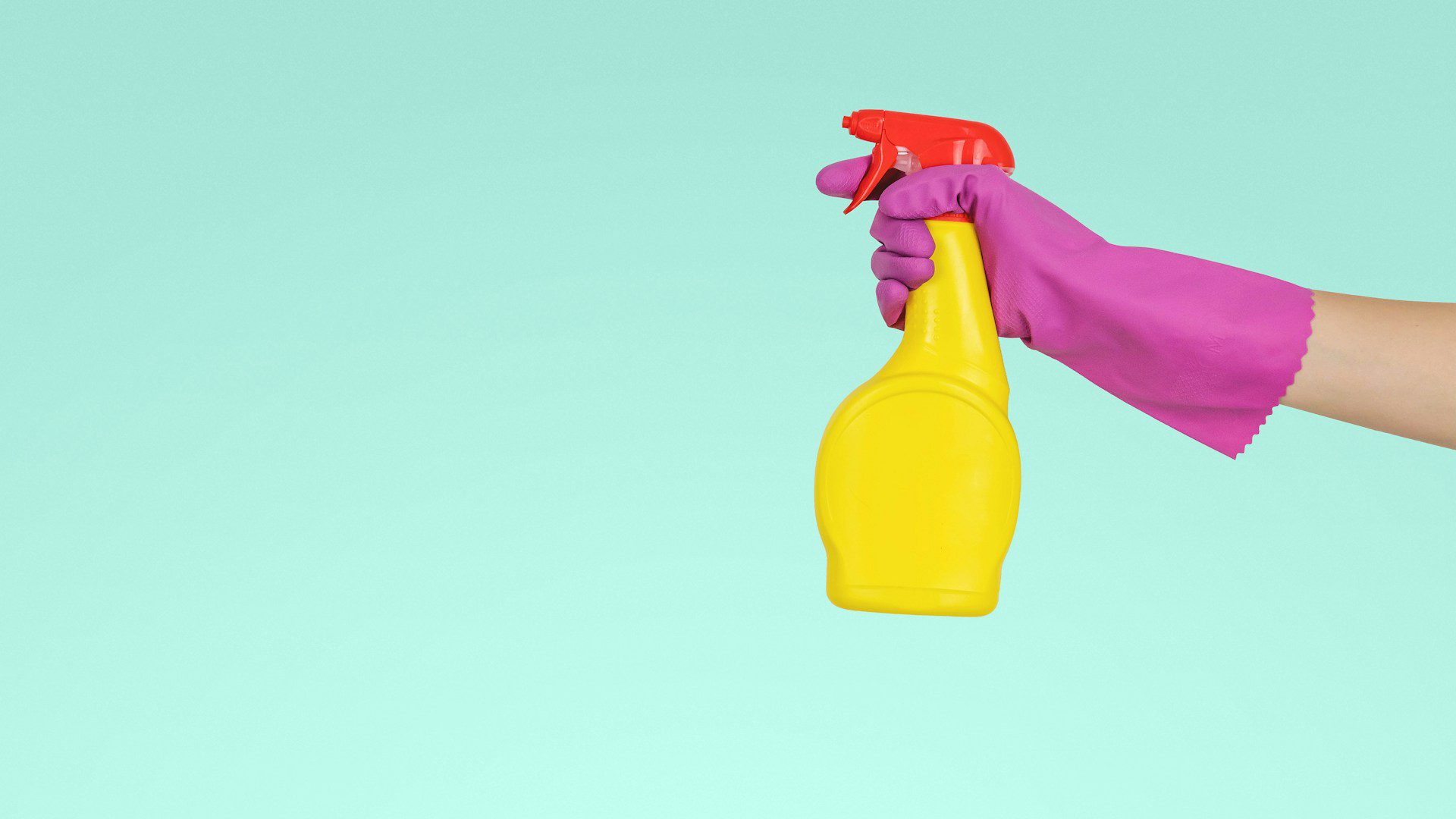 A hand holds a yellow plastic spray bottle.