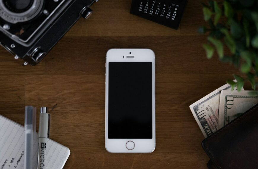 An older gold smartphone lying flat on a wooden table.