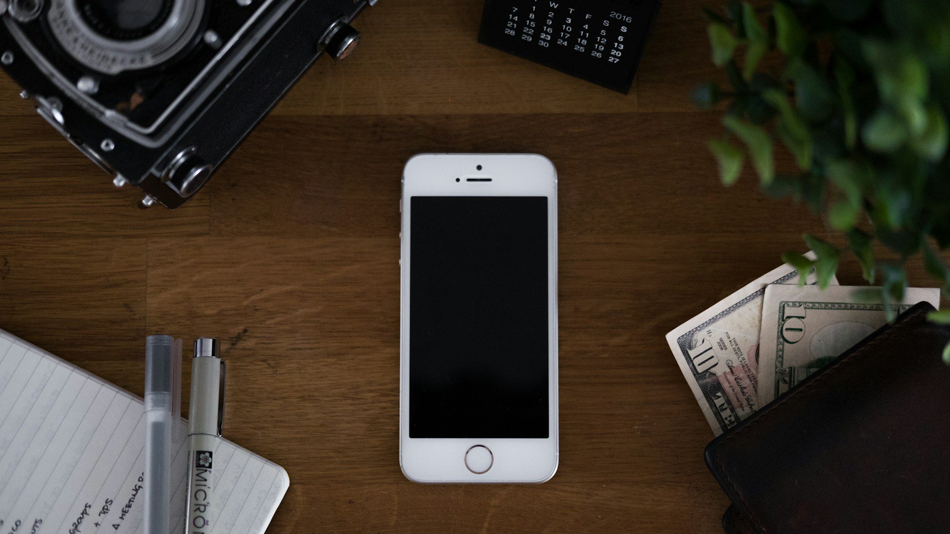 An older gold smartphone lying flat on a wooden table.
