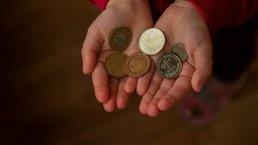 A pair of hands holds a small pile of silver coins.