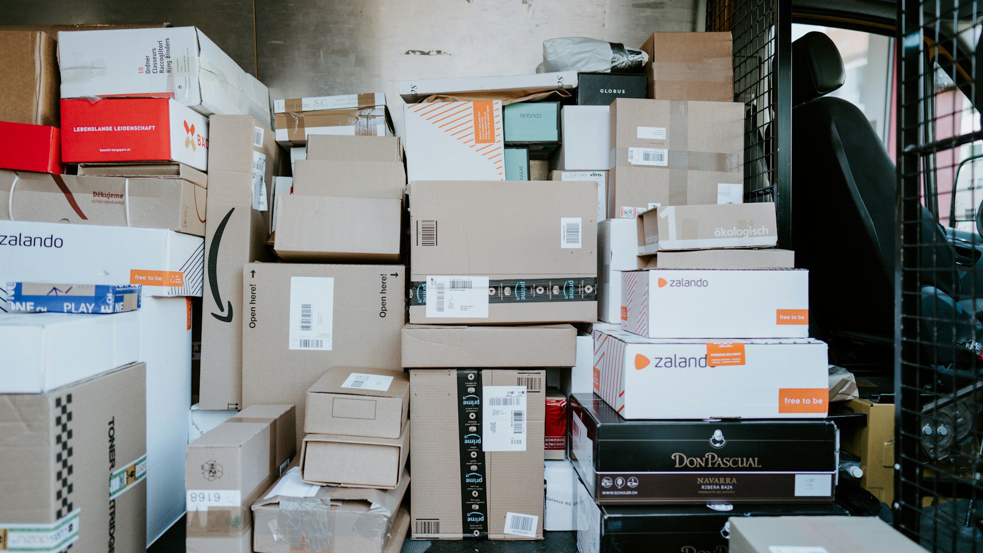 A stack of cardboard shipping boxes inside the back of a delivery van.