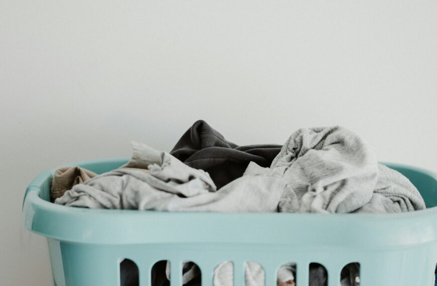 A blue laundry basket holds a pile of clean white clothes.