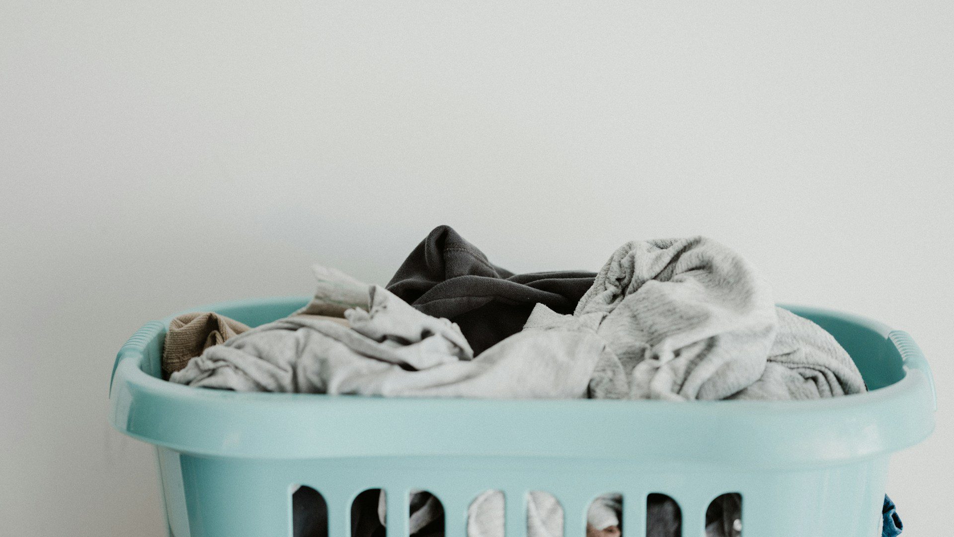A blue laundry basket holds a pile of clean white clothes.